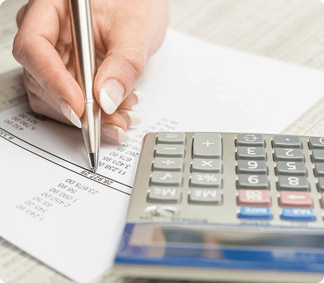 A hand holding a pen and a calculator.