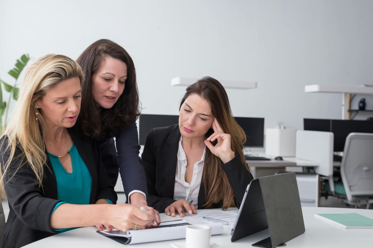 Three women collaborating on a project in an office setting.