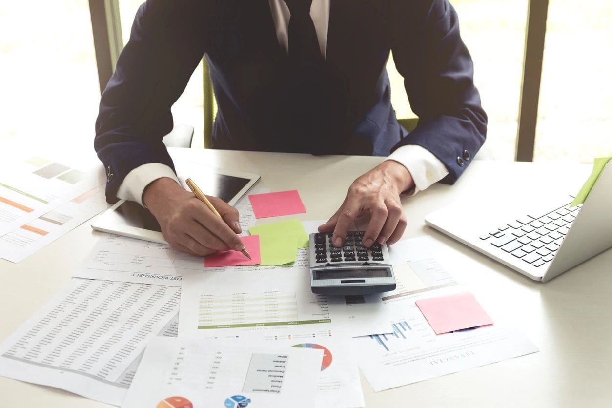 A businessman sitting at a desk with papers and a calculator.
